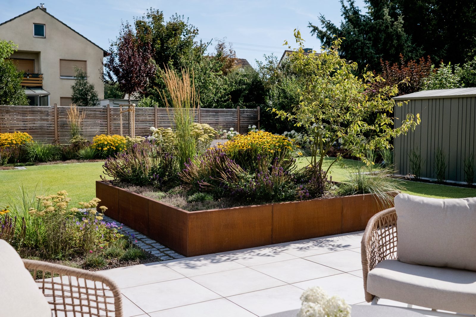 Neu angelegter Garten in Bonn: Terrasse mit Sitzgruppe, Hochbeete aus Cortenstahl und blühende Staudenbeete