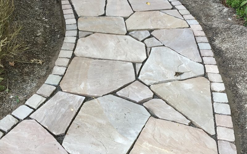 Geschwungener Gartenweg aus verlegtem Naturstein mit sauberer Randeinfassung