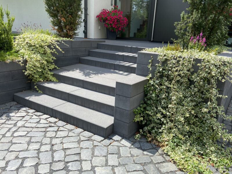 Eingangsbereich mit Natursteintreppe, Pflasterfläche und Rankbepflanzung